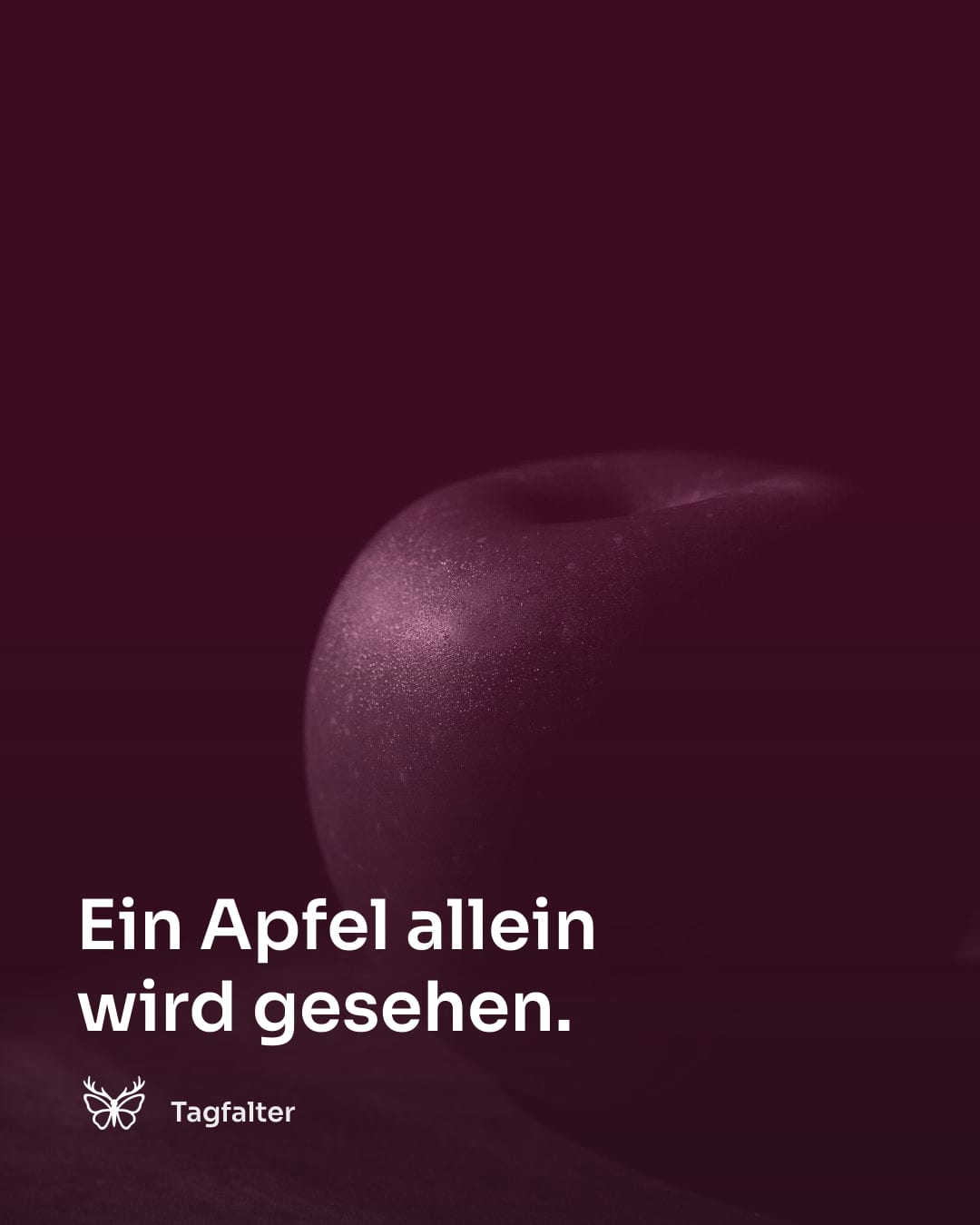 Ein einzelner roter Apfel liegt auf einem schlichten Holztisch.