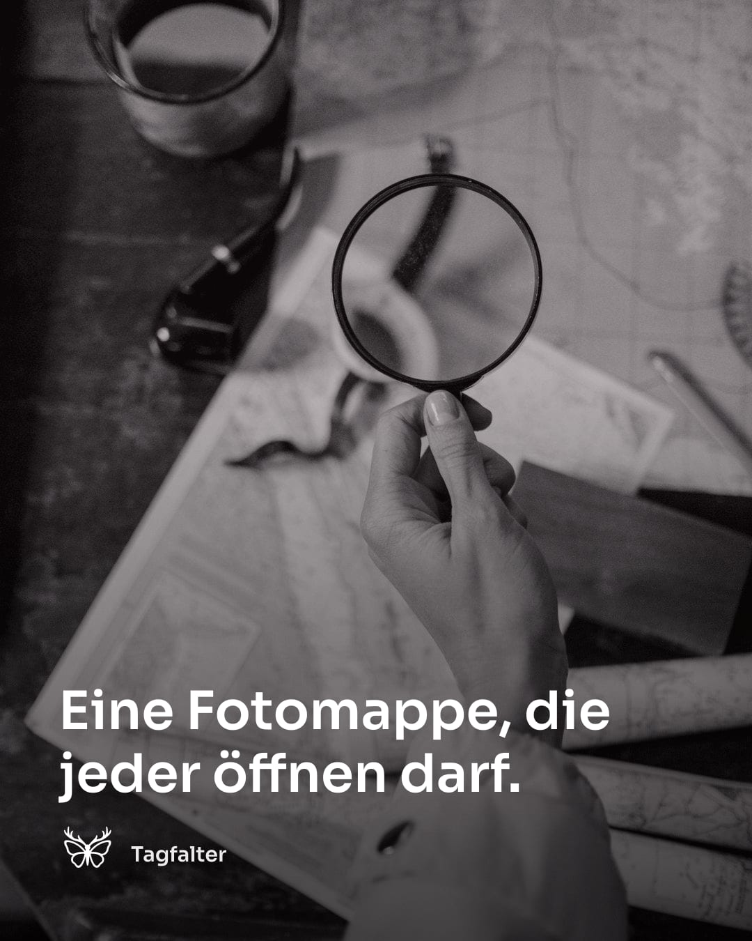 Aufgeschlagenes Fotoalbum mit Lupe auf einem Holztisch