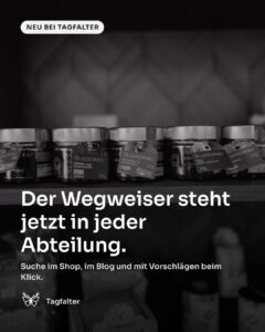 Hände bringen ein Regalschild an einem Holzregal mit Gläsern an. Text im Bild: Neu bei Tagfalter, Der Wegweiser steht jetzt in jeder Abteilung. Suche im Shop, im Blog und mit Vorschlägen beim Klick.